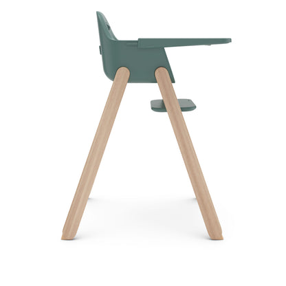 Side view of a green high chair with light wood legs and a tray
