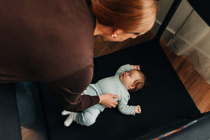 Parent placing a sleeping baby in an UPPAbaby playard