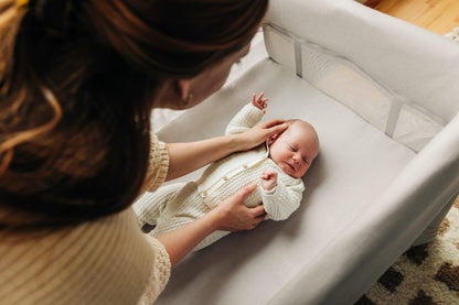 Parent placing a newborn in an UPPAbaby bassinet