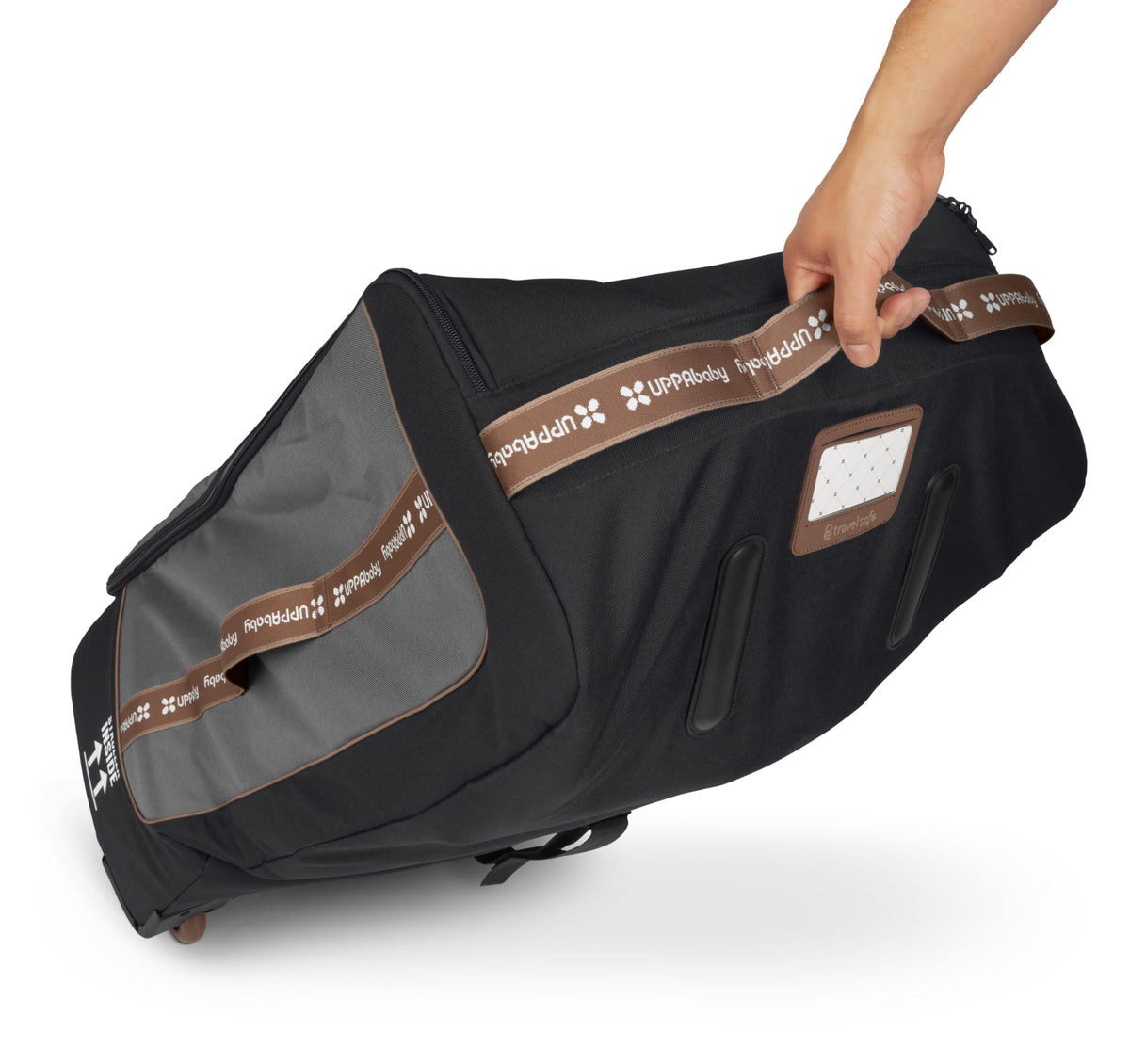 Hand holding a black UPPAbaby travel bag with brown branded straps and a luggage tag