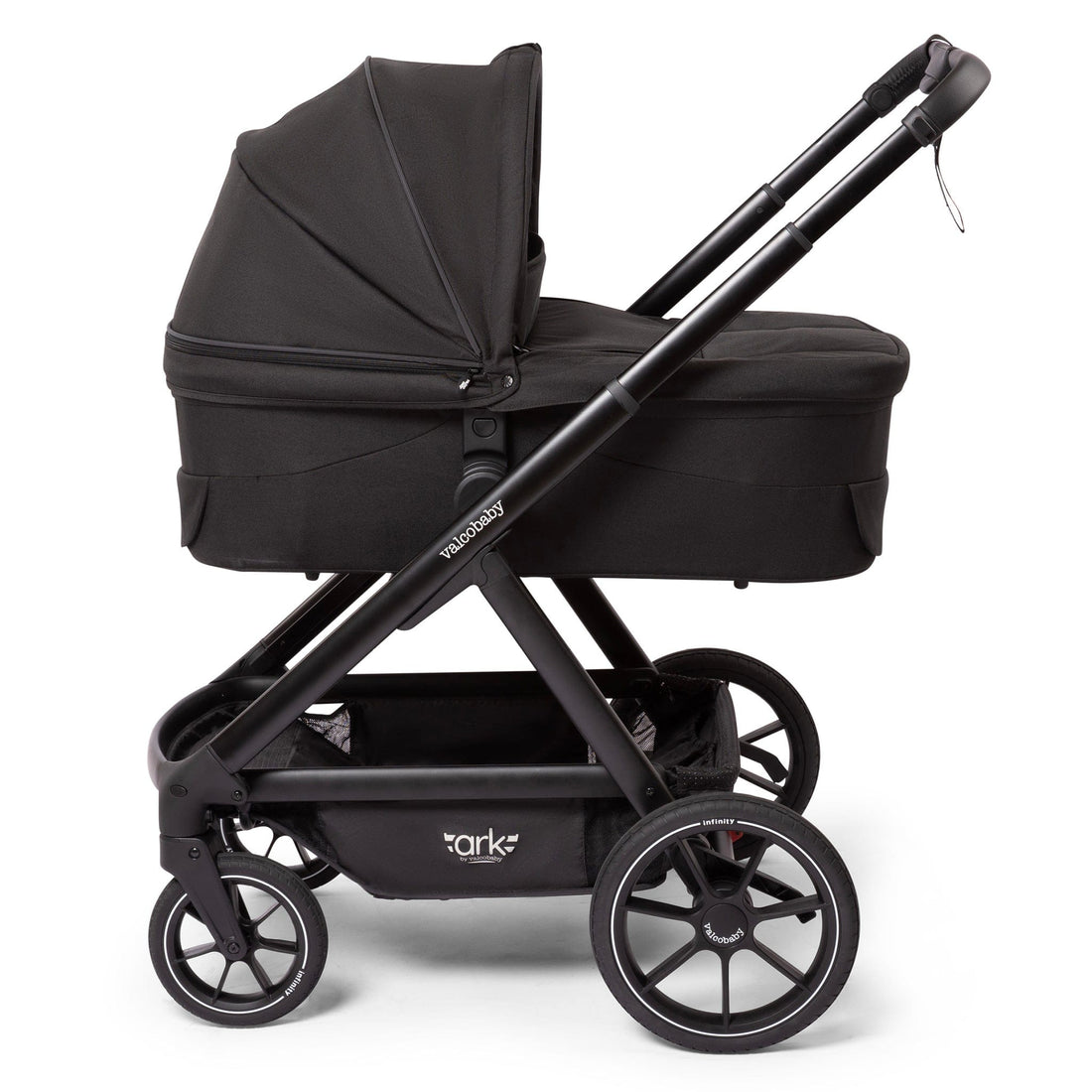 Black Valco OPEN BOX Ark bassinet by Valco Baby, side view with matte black frame, large wheels, and fabric canopy.