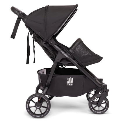 Side profile of a black Valco Baby Slim Twin stroller with storage basket and canopy