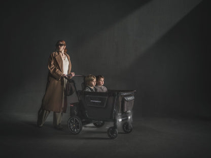 WonderFold Porsche edition stroller with two children inside being pushed by a woman